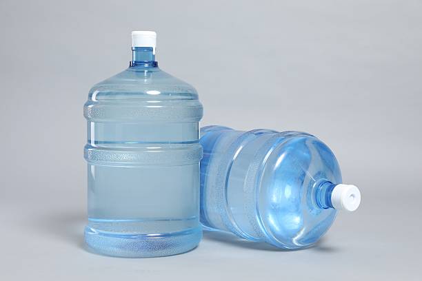 Cooler bottles with water on light grey background, closeup